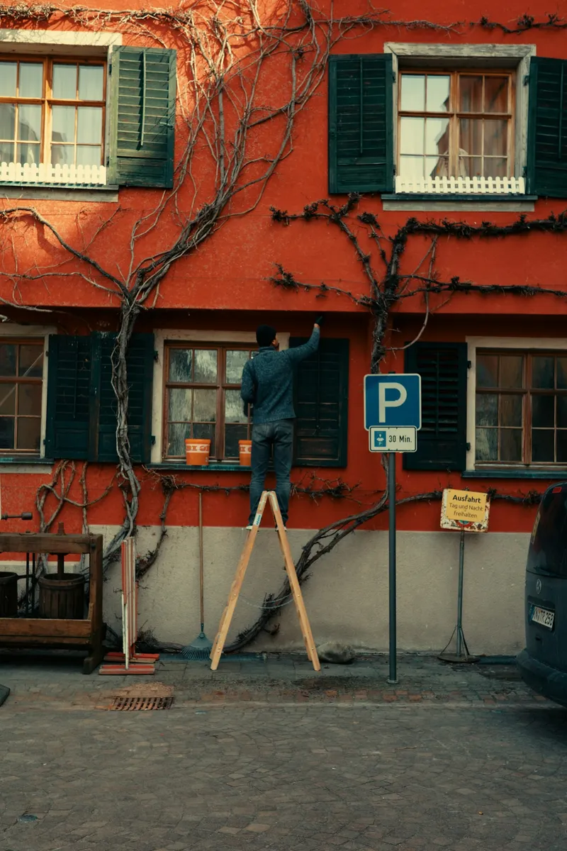 Painter working on exterior walls from a ladder