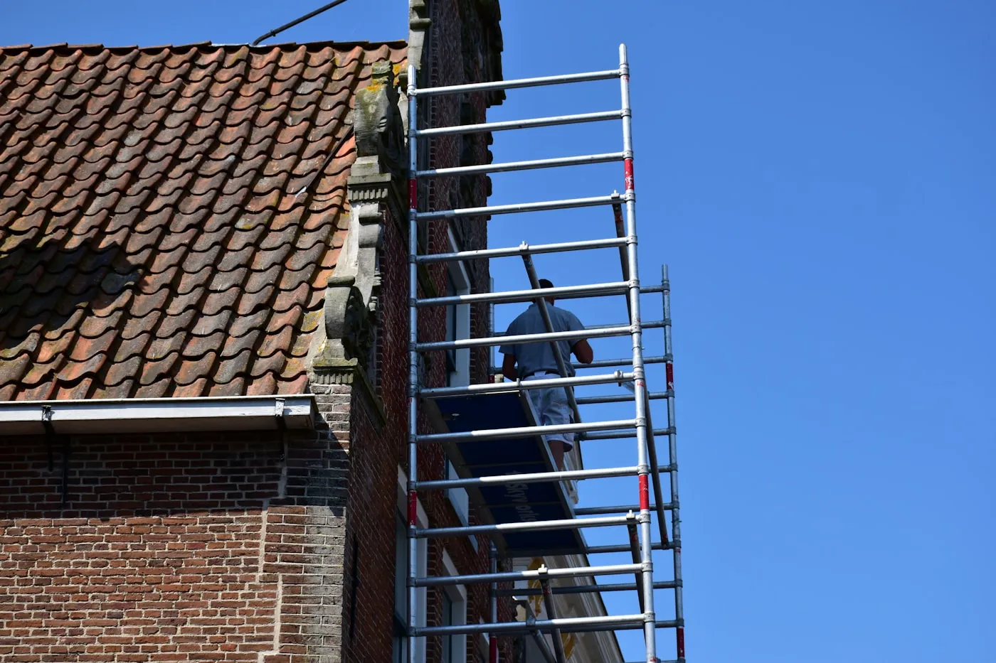 Scaffolder working on scaffolding beside a brick building