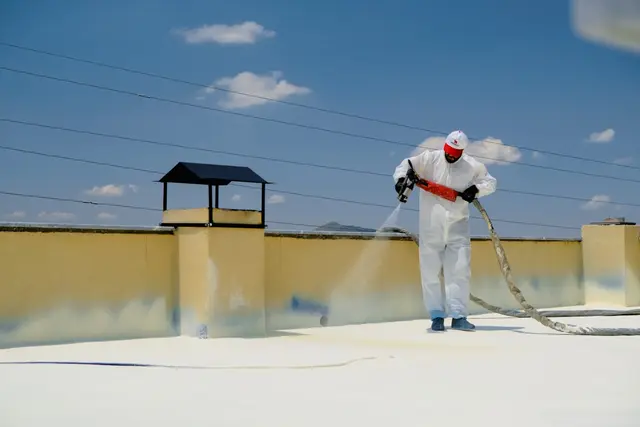 Roofer applying flat roof coating